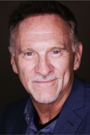 Photo of Gregory F. wearing a blue blazer and a light blue collared shirt.